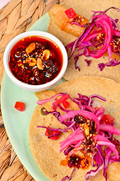 Authentic Mexican fish tacos, Ensenada style, with pickled red onions and peanut chili oil (salsa Macha) on a white bowl