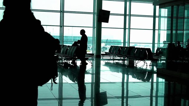 Silhouettes of a traveler walking through a modern airport terminal at dawn