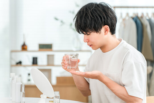 A sick man taking oral medication, supplements, and medicine in the living room.