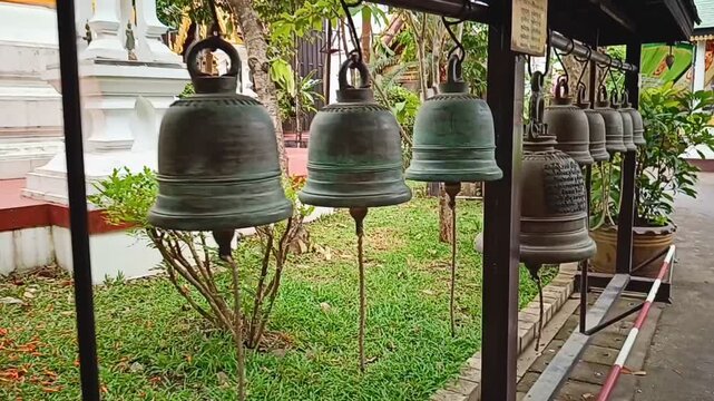 Row of traditional bronze bells in a Buddhist temple complex. Buddhist temple bells for prayer and meditation at Wat Mung Muang, Chiang Rai.