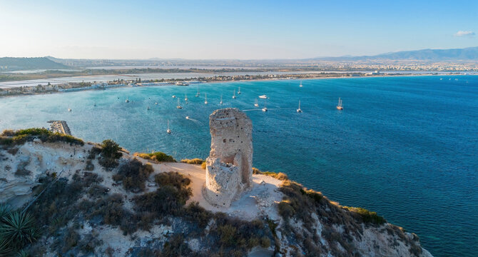 Aerial view of the ruins of Torre del Poetto watchtower on the Sella del Diavolo cliffs overlooking the marina and Poetto beach, Cagliari, Sardinia, Italy
