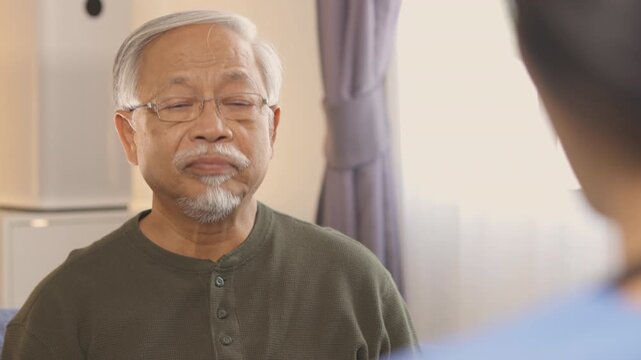 Elderly patient, senior asian man, listening attentively during serious medical consultation. caregiver, nurse, or doctor discusses important health concerns