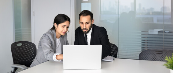 Naklejka premium Multiethnic colleagues working together in office, reviewing information on laptop. Client consultation, project planning, business data analysis, strategy development, collaborative decision-making