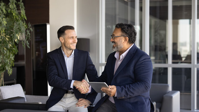 Two businessmen expressing respect, handshaking during workday in office. Gesture of positive outcome of discussion, business relationships, professional trust and successful workplace communication