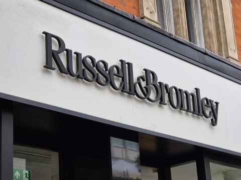 London UK 06.07.2025 Russell And Bromley storefront sign on modern retail facade showcasing british luxury footwear brand in city shopping street environment