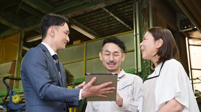 工場でタブレットを見る夫婦と信金営業や訪問営業マンの打ち合わせ経営支援のコンサルやビジネスシーンの動画　借り入れや機械の提案などの商談や法人営業のイメージクローズアップ