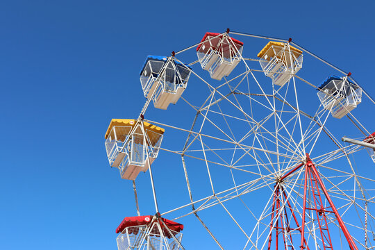 Colorful ferris wheel gondolas against a bright blue sky at a carnival or amusement park