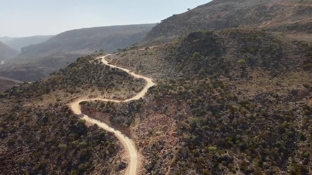 Aerial winding dirt road on rugged mountain landscape. Wadi Dirhur, Sokotra, Yemen.