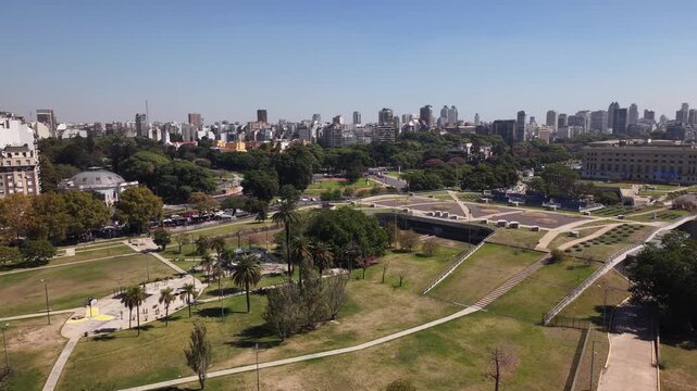 Aerial pan left over the green parklands of Recoleta, revealing the UBA Law Faculty building and the modern skyscrapers of the Buenos Aires skyline
