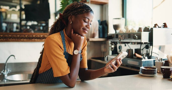 Text, reading and barista in cafe with phone, chat or social media update on work break. Message, digital or black woman in restaurant with tech, business review or online communication in free time.