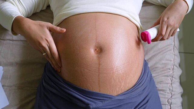 Pregnant Woman Applying Moisturizing Cream to Belly with Stretch Marks