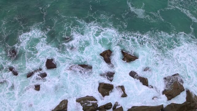 Surf moves and boils around the rocks on a calm day below the Sea Cliff bridge, viewed from the bridge walkway, part of the Grand Pacific drive just South of Sydney in New South Wales, Australia.