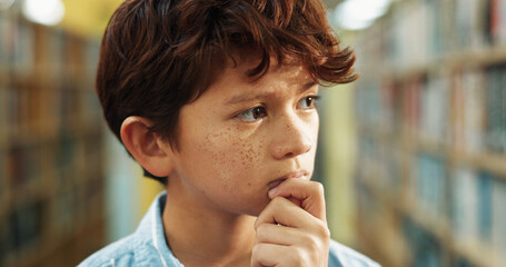 Education, student and thinking with boy in library of academy for decision, ideas or vision. Bookshelf, inspiration and learning with child pupil at school for development, future or growth © peopleimages.com