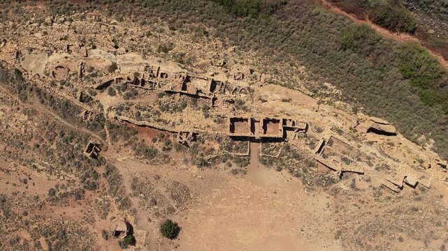 A top down drone shot explores the decaying stone walls of a remote historical site. The vertical perspective highlights the intricate textures of the ruins against the rugged high desert terrain.