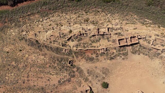 A vertical drone view looks straight down onto a desolate ghost town. The ruined stone buildings and arid landscapes offer a cinematic and unique perspective on historical desert architecture.