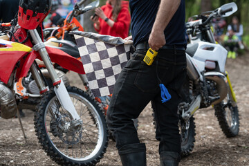 Naklejka premium Candid moment of a racing official with a checkered flag in a busy paddock.