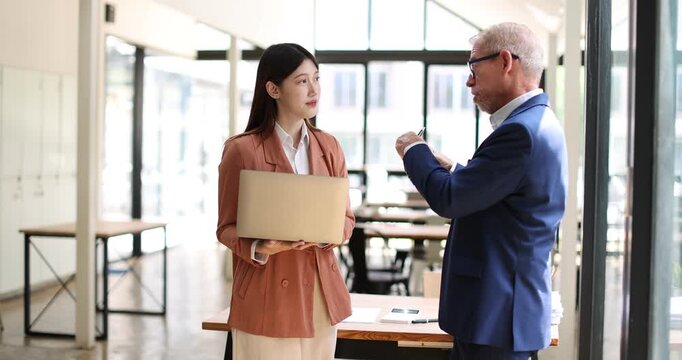 Two business people partners coworkers colleagues discussing about work at office stairs. Female workers manager showing document contract graphs and charts for her mature senior boss
