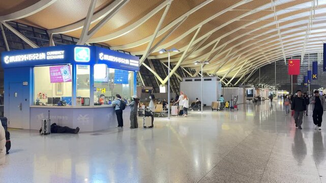 Shanghai Pudong International Airport, Shanghai, China, March 30, 2026: Interior view of currency exchange counter with travelers and seating area.