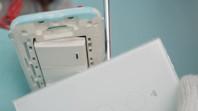 Technician uses a screwdriver to installing modern switch, touch or smart phone-controlled on-off light, Smart Home.