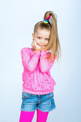 Funny kid with playful fashion pose. Cute child in pink and denim outfit. Studio portrait with modern style. Fun childhood expression and trendy look. © Volodymyr
