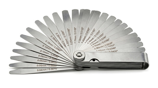 A set of automotive feeler gauges, used for measuring clearances between parts, displayed in a fan-like pattern against a white background