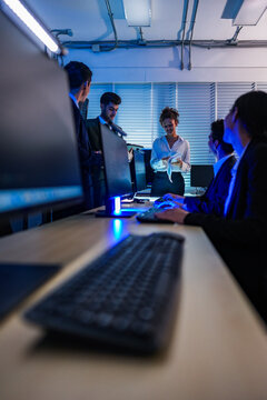 IT specialists working on network security monitoring in a modern office at night, focused on analyzing cyber threats and ensuring system data protection.