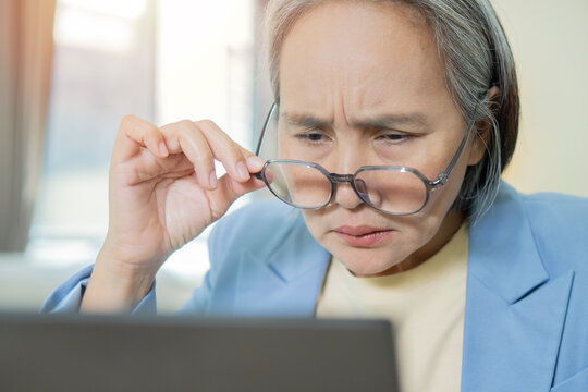 Stressed mature woman sitting at workplace, holding eyeglasses, have a vision problem
