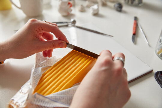 Close-up of Artist's Hands Cutting a Yellow Block of Polymer Clay with a Metal Blade