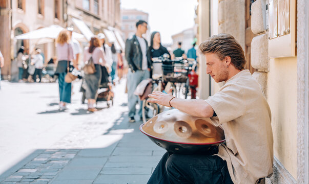 Street musician playing handpan instrument outdoors
