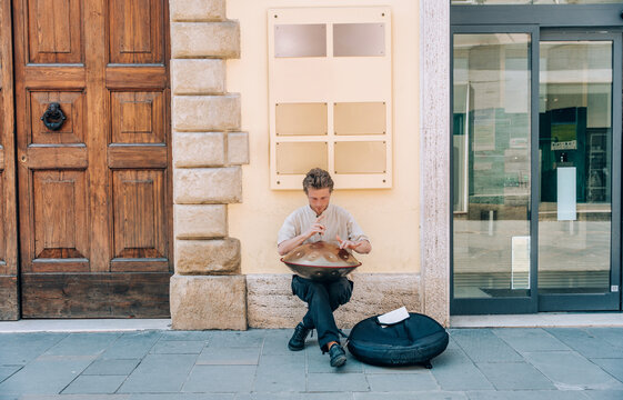 Street musician playing handpan instrument outdoors