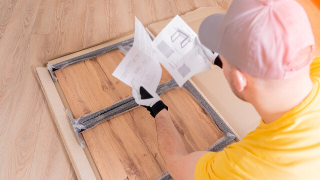 The furniture assembler opened the instructions for assembling the table. A man collects a table for the living room in close-up. Assembling new furniture yourself. High quality photo