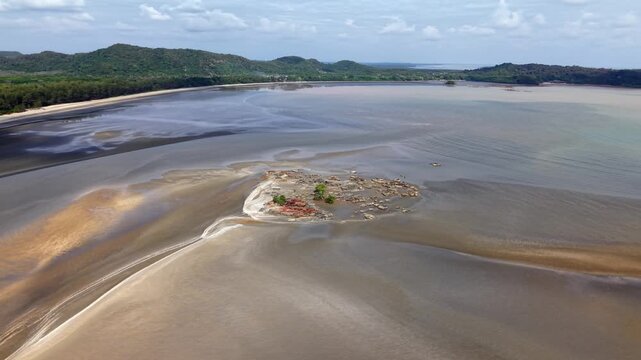 Beneath a clear sky, water recedes from a vast shoreline