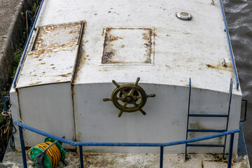 Top view of weathered boat cabin with ship wheel and blue railing © PRAPS