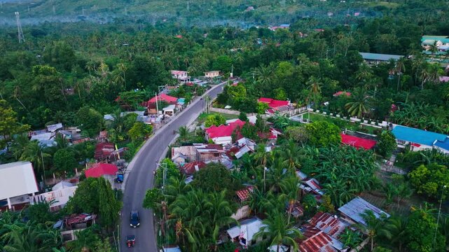 Cinematic flight over Lower Anongan village with houses at dusk in Alegria Cebu