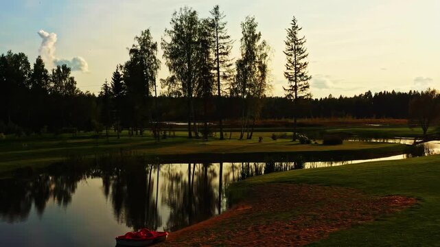 Golf course water hazard reflecting sunset sky with a red pedal boat