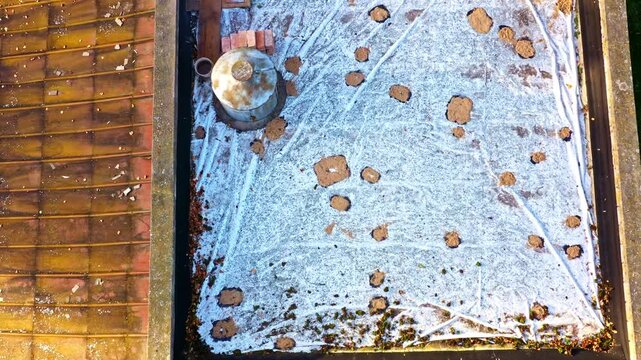 Flat roof showing ongoing membrane waterproofing with repair materials and chimney flue