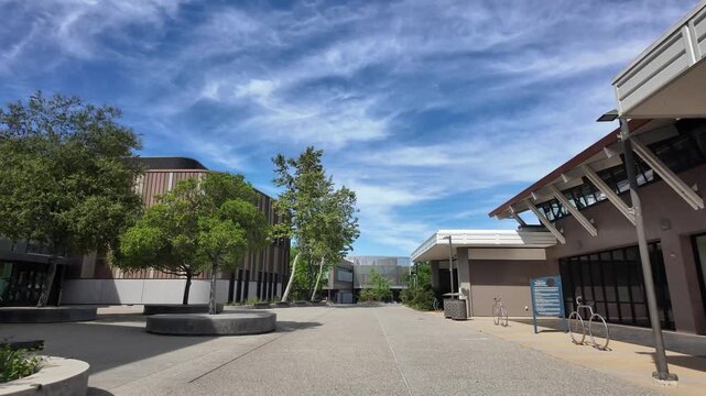 Point of view shot walking through the deserted modern campus of West Valley College in Saratoga, California, showing contemporary architecture and landscaped courtyards under a blue sky