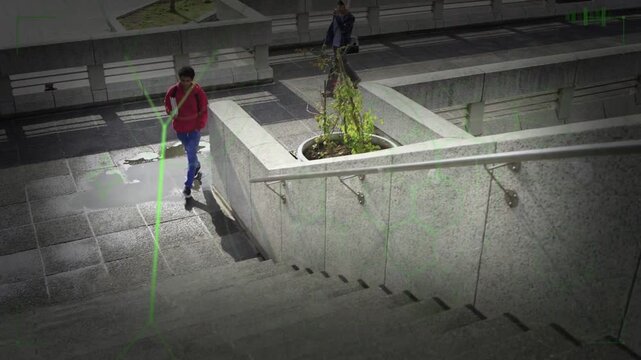 Green overlay appearing, tracking man in red jacket descending stairs carrying box for surveillance