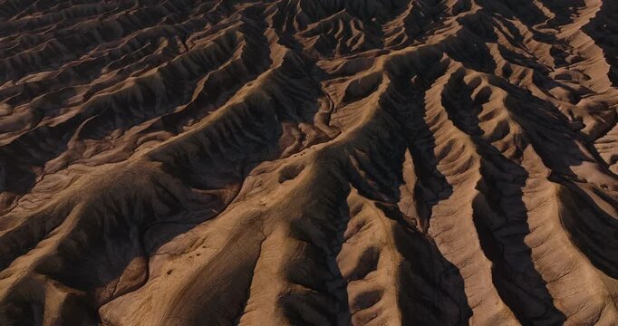 Aerial tilt up of intricate erosion patterns across dry Utah desert badlands terrain