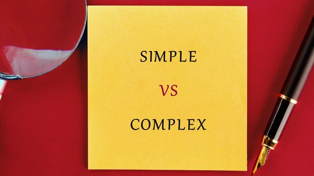 A yellow sticky note displays simple versus complex words, highlighted by a pen and magnifying glass on a vibrant red surface