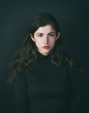 Minimalistisches Portr&auml;t einer jungen Frau im dunklen Look &ndash; ruhiger Ausdruck, sanftes Licht, Mode, &Auml;sthetik, Studio, introspektiv, Lifestyle, Copyspace, isoliert