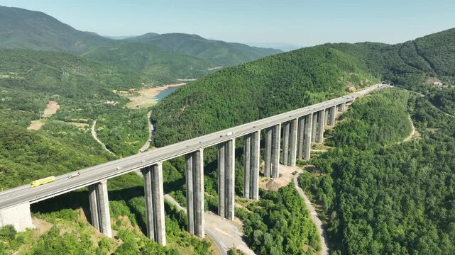 Aerial view of a highway viaduct bridge spanning a lush green mountain valley. Modern transportation infrastructure, engineering. Road trip travel