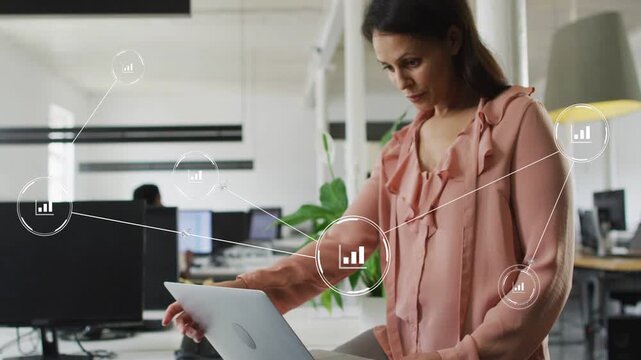 Mid-adult woman using trackpad at desk, activating data nodes and reviewing business analytics