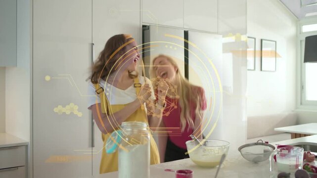 Two women dancing mixing batter raising spoon causing clear ring overlay swapping spoon mixing food