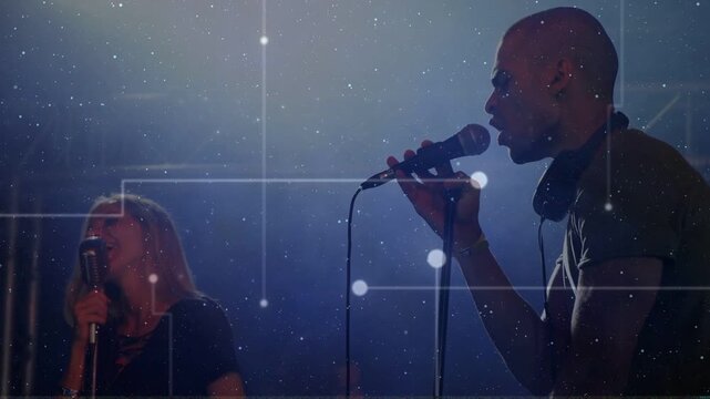 Male singer starting lead vocal, female harmonizing in duet, mics, node overlay floating over stage