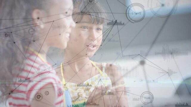Two girls raising stylus in bright classroom, network overlay shifting across faces and icons