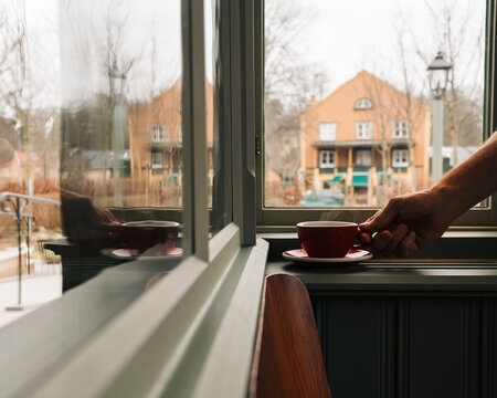 person holding a steaming coffee on a window in a cafe