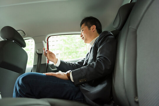 車内でスマートフォンを操作する40代男性