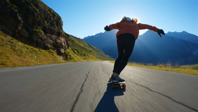 woman skateboarding and making tricks between the curves on a mountain pass.