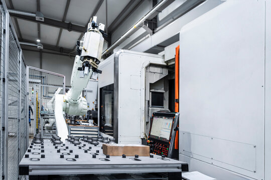 White robotic arm with CNC machinery in factory
